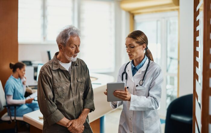 General practitioner and her senior patient using digital tablet at doctor's office.